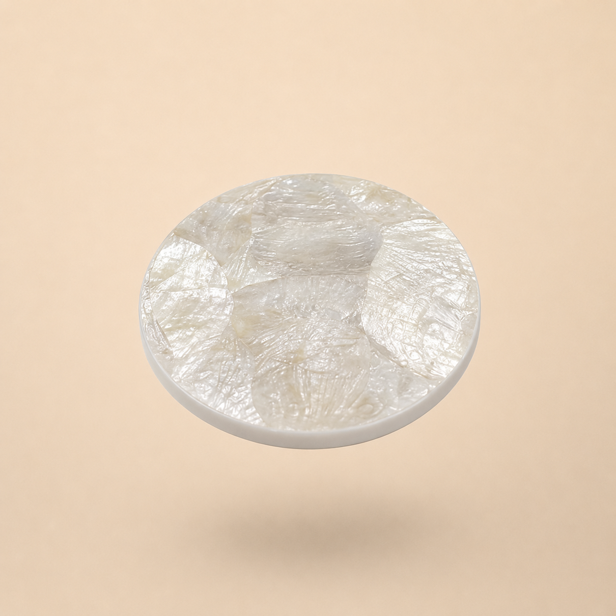 Round mother of pearl coaster on beige background