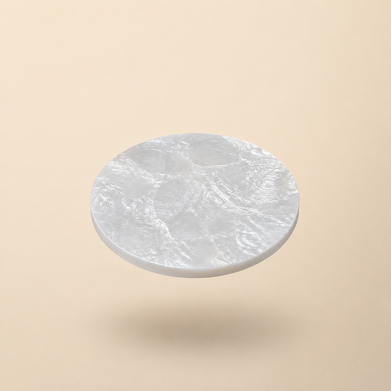 Round mother of pearl coaster on a beige background